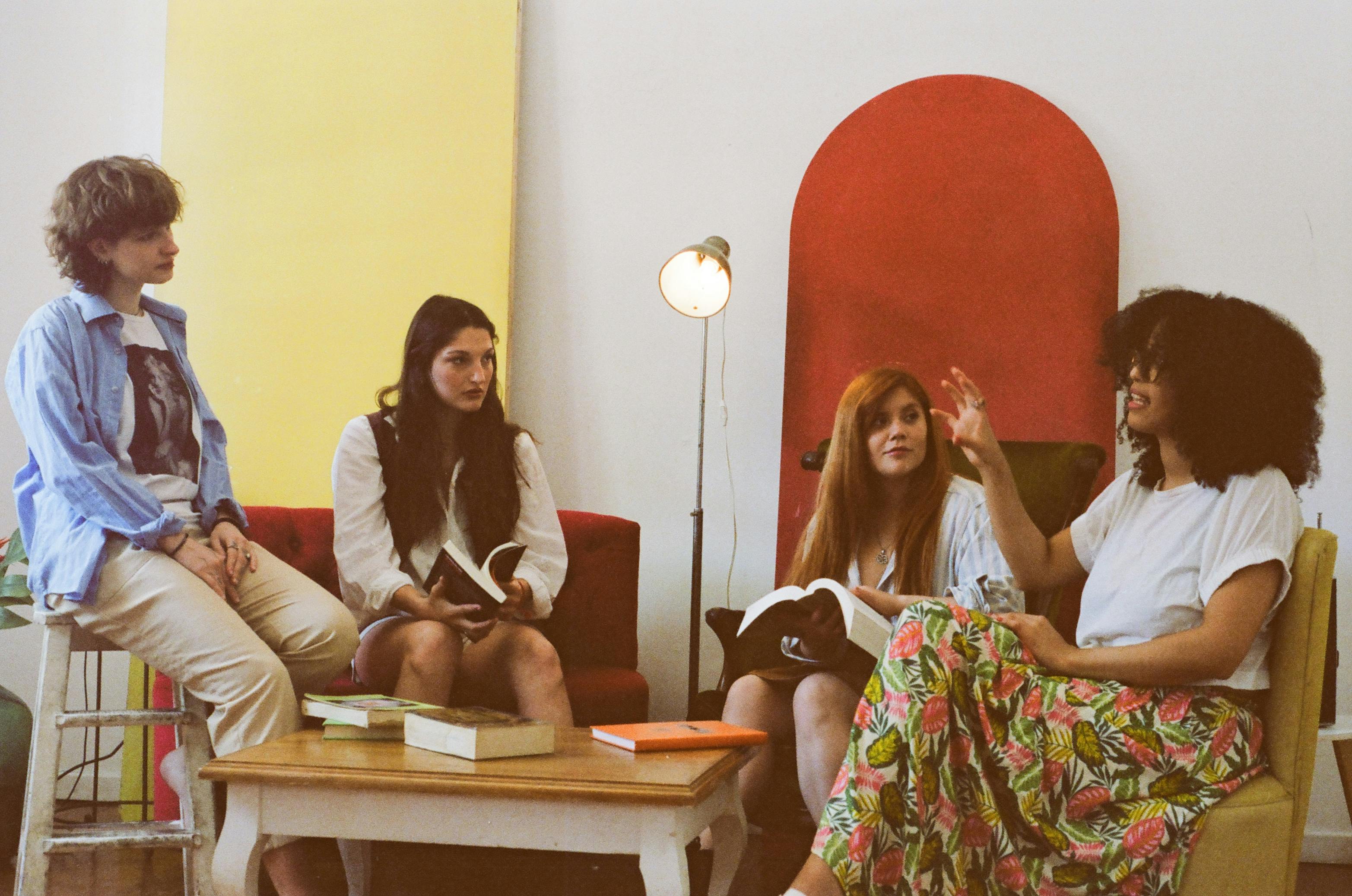 A diverse group of women gathered together reading and talking, sharing a moment of connection and growth
